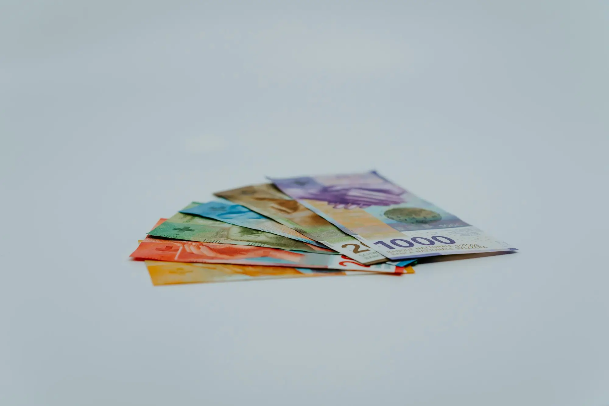 A stack of Swiss banknotes on a white surface
