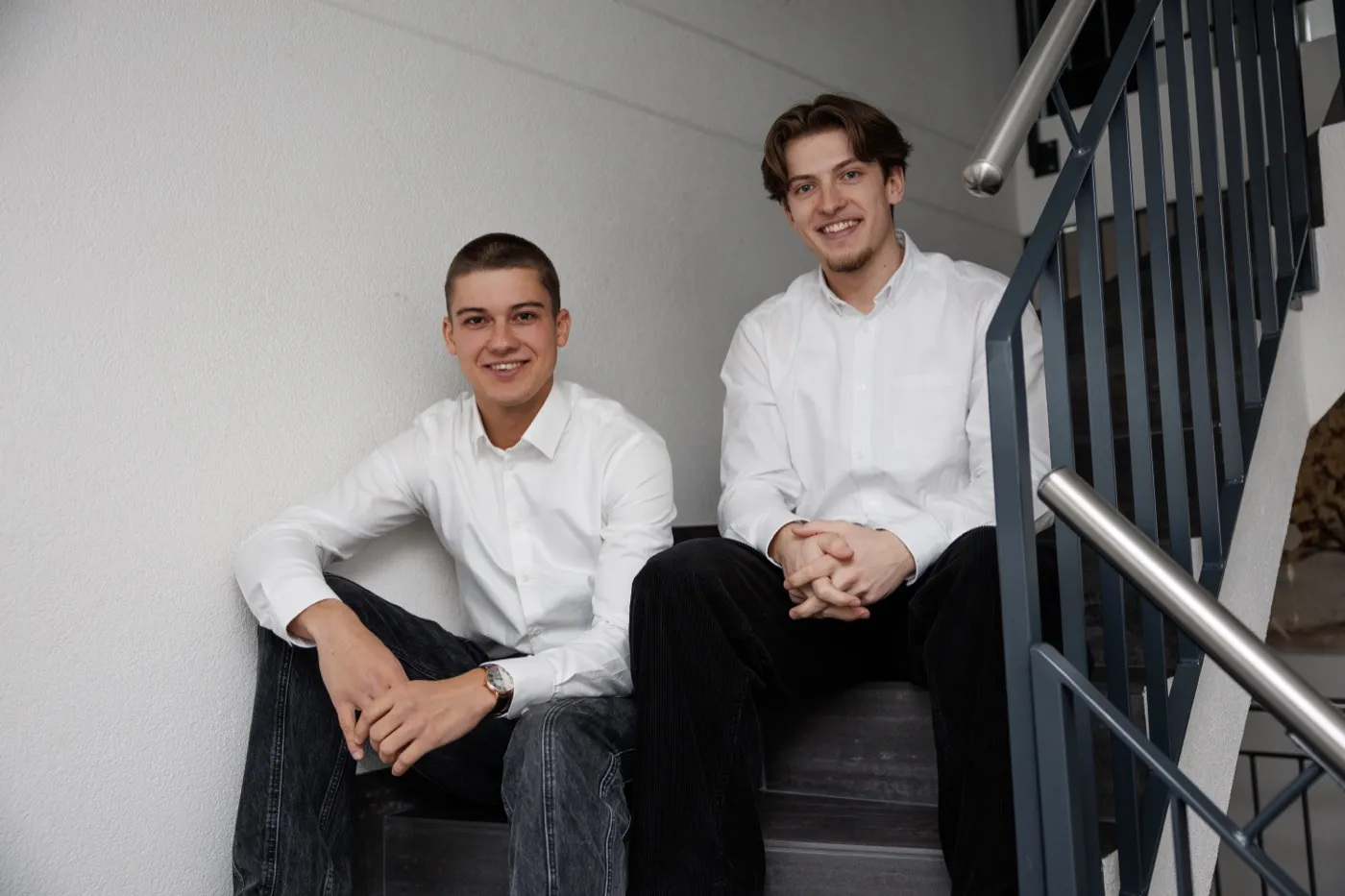 Ramon Peter und Bastian Strohschein sitzen gemeinsam auf einer Treppe