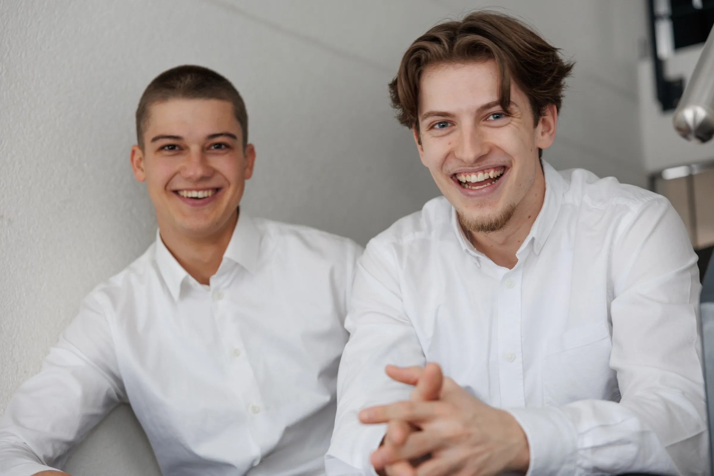 Ramon Peter und Bastian Strohschein sitzen lachend auf einer Treppe